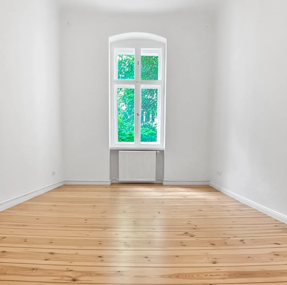Abgeschliffene Holzdielen in einer Berliner Altbauwohnung neben einem aufgearbeiteten Altbaufenster
