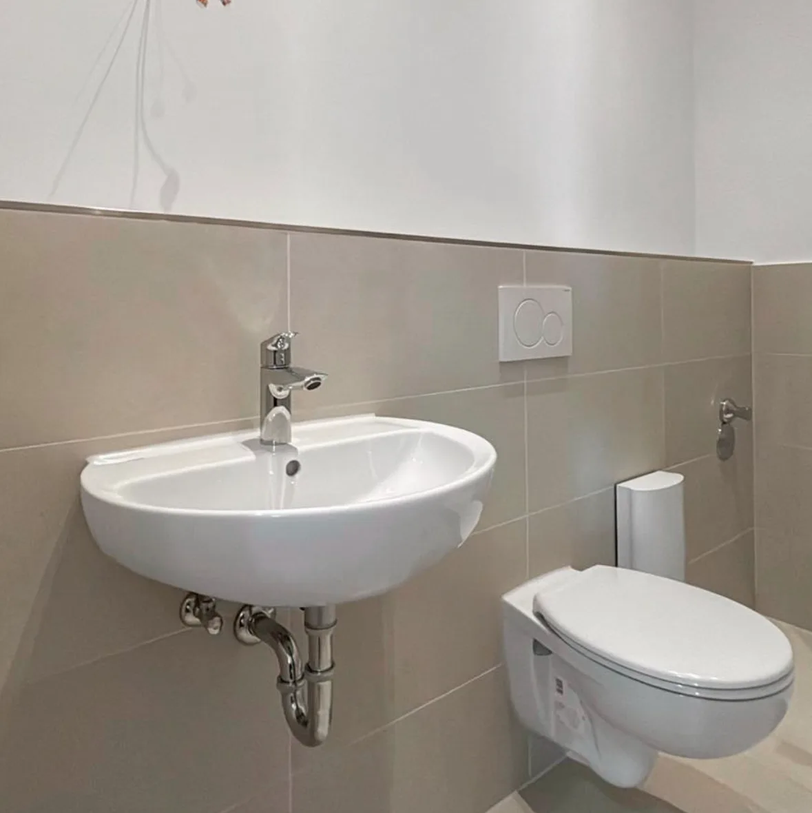 Wandwaschbecken und wandhängendes WC mit Betätigungsplatte