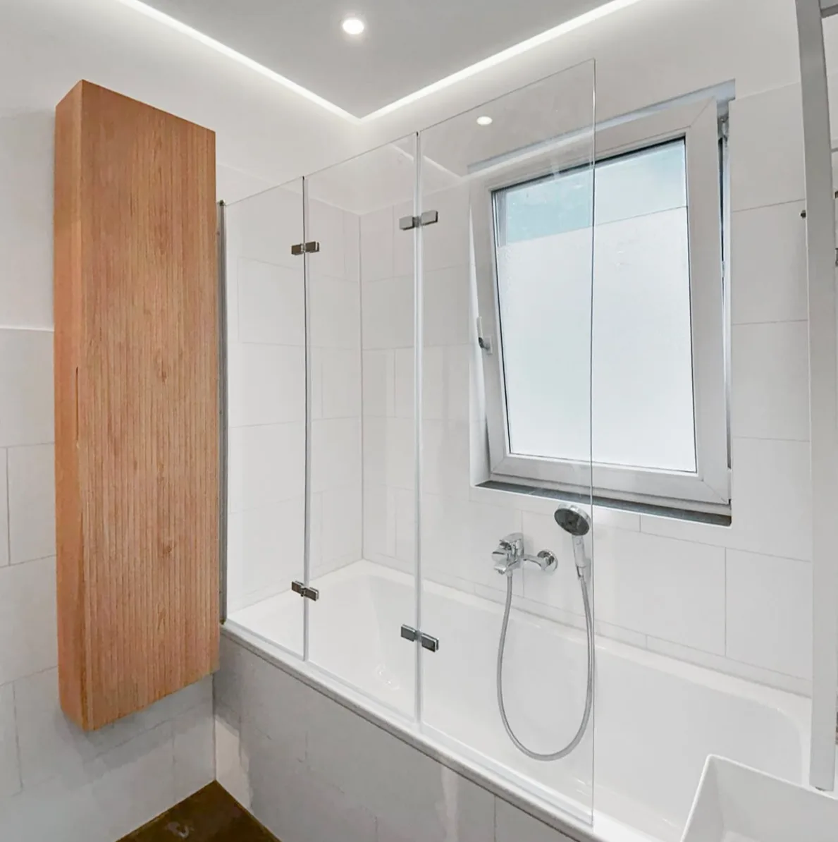 Einfaltbare Glasabtrennung an der Badewanne unter der Decke mit Schattenfuge