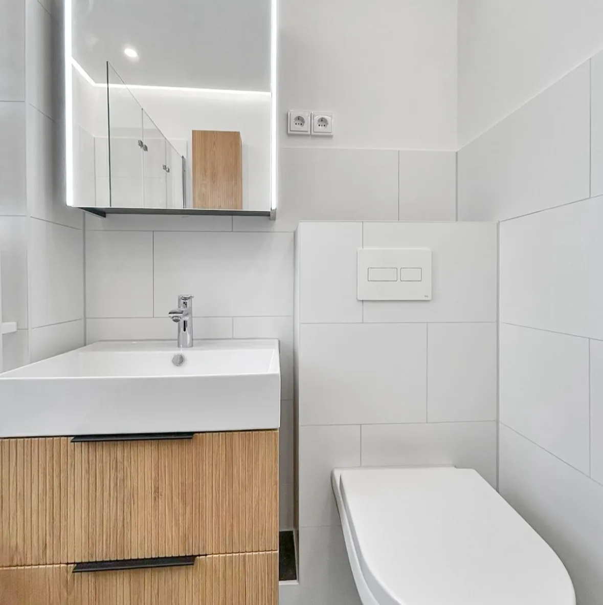 Waschtisch mit Holzunterschrank neben dem Wand-WC mit Vorwandinstallation
