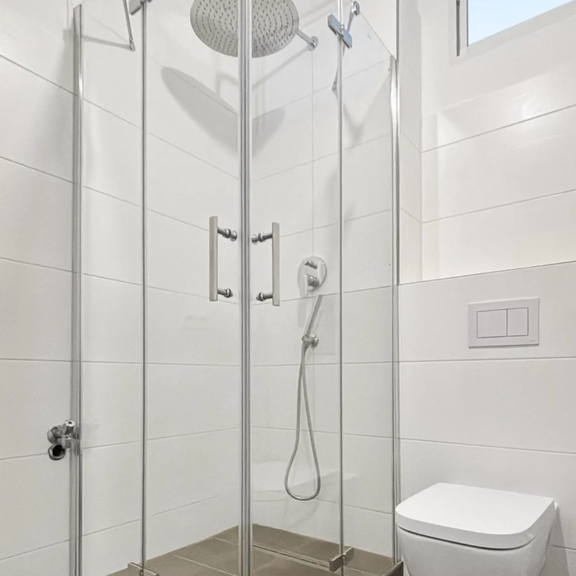 Dusche mit Eckeinstieg und Echtglas-Abtrennung neben dem wandhängenden WC