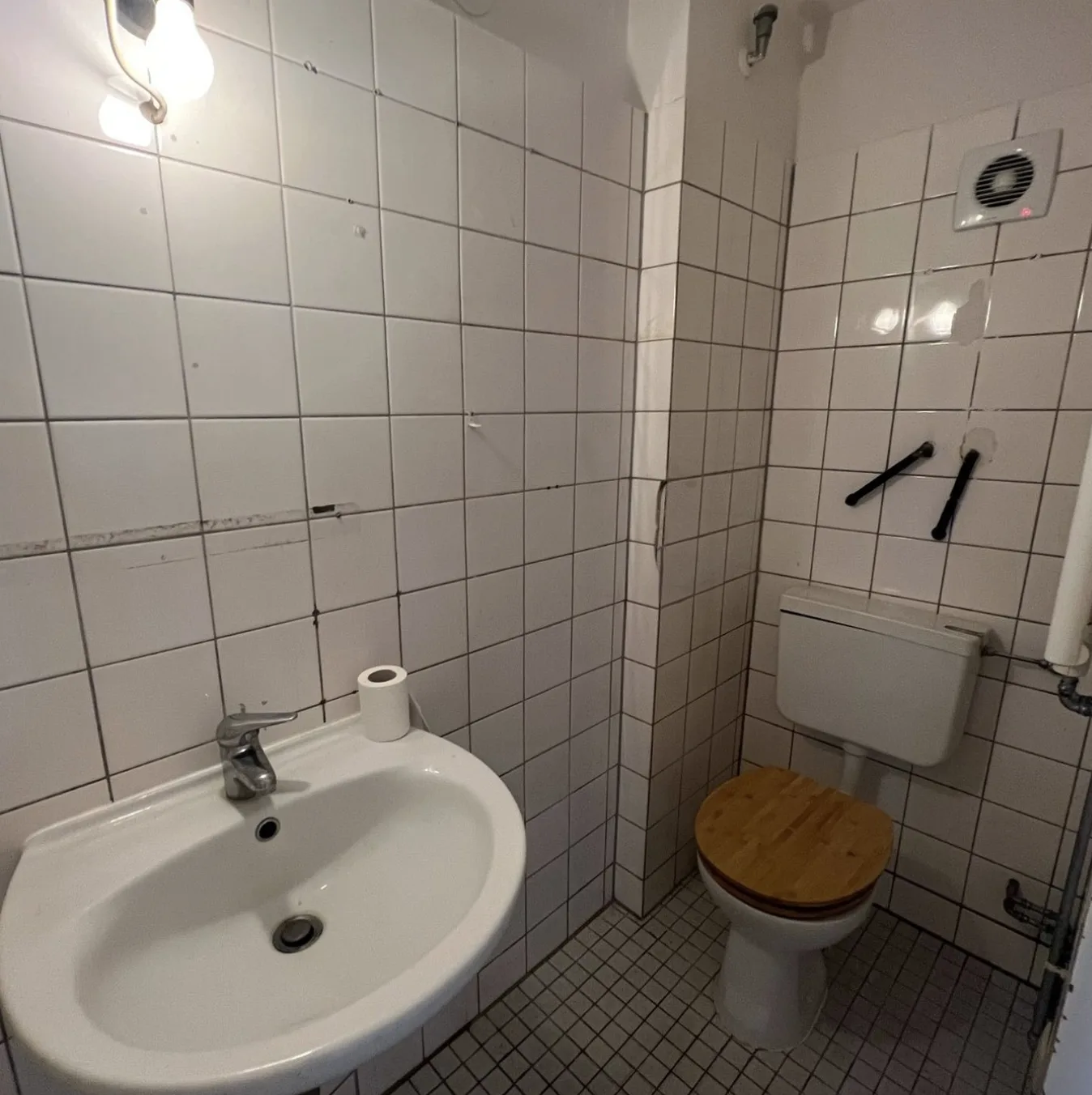 Vorher: weiß geflieste Wände, Mosaikboden, Stand-WC mit Aufputz-Spülkasten