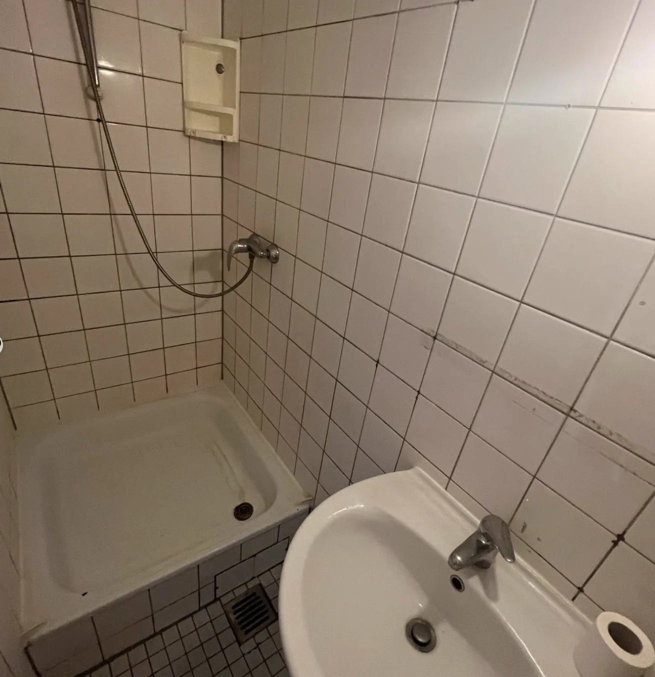 Vorher: alte Duschwanne mit Fliesenspiegel und offenem Bodenablauf