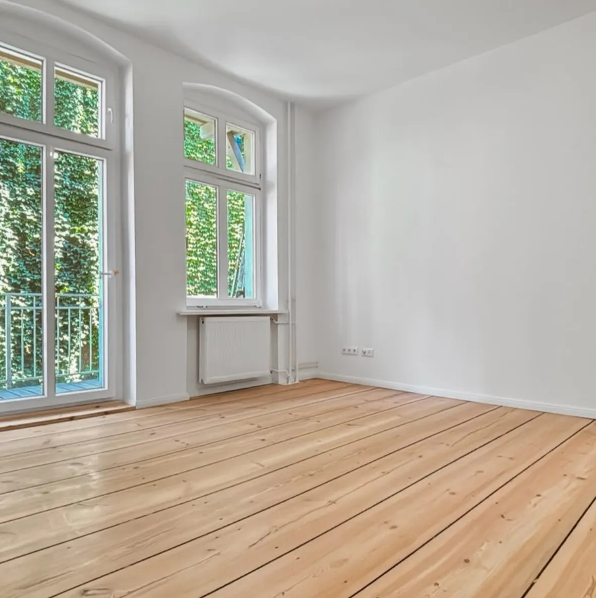 Wohnzimmer mit abgeschliffenen und versiegelten Dielen und Balkontür